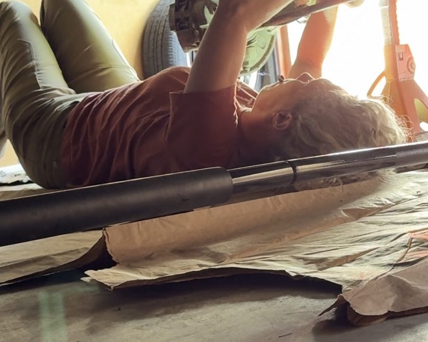 Heather Jacks performing mechanical repairs on Buster, her Sumatra Green 1973 VW Westfalia bus, preparing for a 1,000-mile road trip.